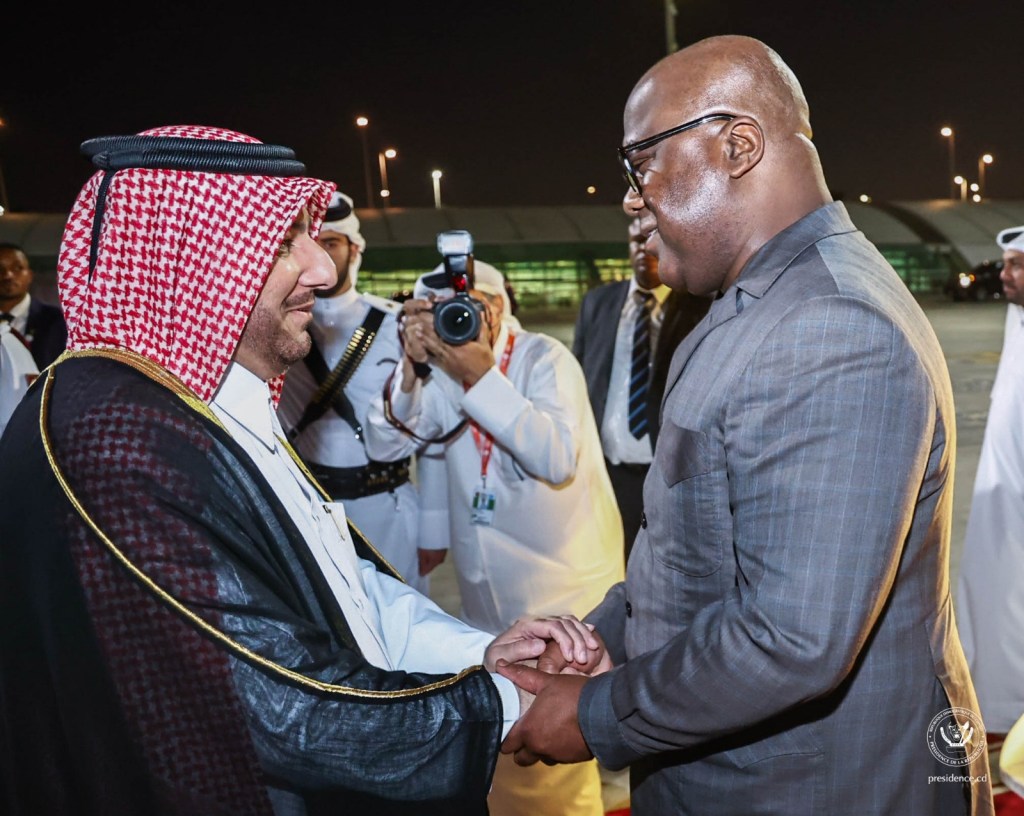 Le Président Félix-Antoine Tshisekedi Tshilombo serre la main d'une autorité qatarie à son arrivée à Doha, entouré de membres de la sécurité et de presse.