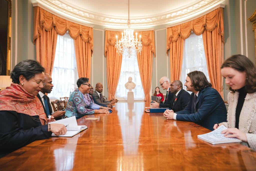 Réunion entre la Première ministre de la République démocratique du Congo, Judith Suminwa Tuluka, et le Vice-premier ministre britannique, David Lammy, autour d'une table dans une salle de réunion élégante.